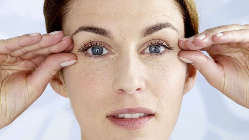 A woman holds hands near her eyes